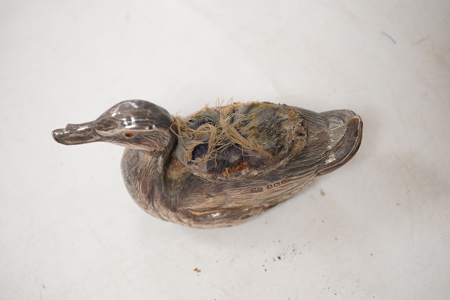 An Edwardian novelty silver mounted pin cushion, modelled as a duck, by Abrahall & Bint, engraved with 'feather' decoration and glass eyes, Birmingham, 1906, length 94mm, height 59mm(a.f.).